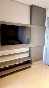 a living room with a tv on a wall at Estúdio Aconchegante no 24º andar do Ed. Vertigo. in Campo Grande