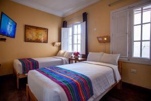 een hotelkamer met 2 bedden en 2 ramen bij Eco Inn in Cuzco