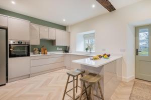 una cucina con armadi bianchi, bancone e sgabelli di Willow, a luxury rural retreat a Staveley