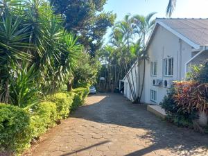 un vialetto che conduce a una casa bianca con palme di The Sanctuary Guesthouse a Empangeni