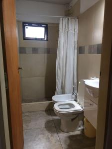 a bathroom with a toilet and a sink and a window at departamento microcentro in Paraná