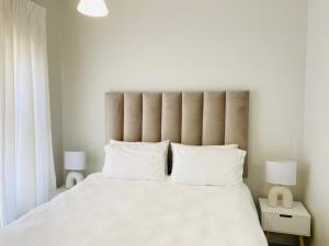 1 dormitorio con 1 cama blanca grande y 2 lámparas en Greencreek Beautifully furnished apartment, en Pretoria