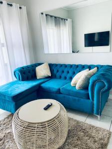 Sofá azul en la sala de estar con mesa en Greencreek Beautifully furnished apartment, en Pretoria