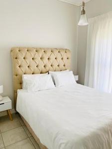 1 dormitorio con 1 cama blanca grande y cabecero grande en Greencreek Beautifully furnished apartment, en Pretoria