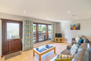 ein Wohnzimmer mit einem Sofa und einem TV in der Unterkunft Bluebell Lodge 7 with Hot Tub in Newton Stewart