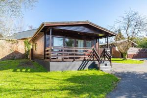 ein Haus mit einer Veranda und einer Treppe im Gras in der Unterkunft Bluebell Lodge 7 with Hot Tub in Newton Stewart