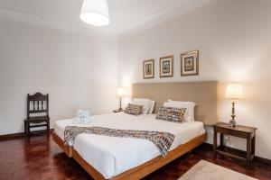 a bedroom with a white bed with two lamps and a chair at GuestReady - Office Residence 3 in Porto
