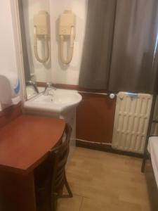 een kleine badkamer met een wastafel en een tafel bij Hotel Continental Amsterdam in Amsterdam