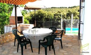 una mesa y sillas en un patio con piscina en Cortijo Los Petronilos, en Las Lagunillas