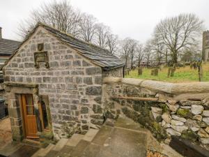 an old stone house with a stone wall at Woodbine Retreat in Buxton