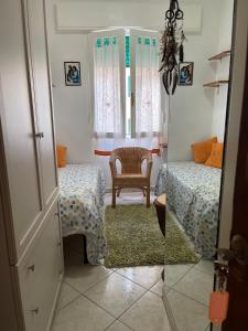 a small room with two beds and a chair at Giuly's Room in Porto Santo Stefano