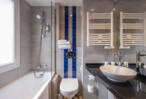 y baño con lavabo, aseo y bañera. en Hôtel Du Vieux Saule en París