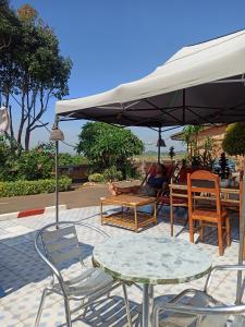 uma mesa e cadeiras debaixo de um guarda-sol com pessoas sentadas em Chez Jeanne Auberge em Talata-maty