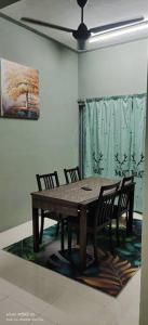 uma mesa de madeira e cadeiras num quarto com uma pintura em Homestay Lumut em Lumut