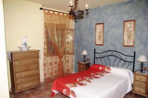 a bedroom with a bed with a red blanket and a dresser at Rural Fábrica del Azúcar 1 in Pozo Alcón