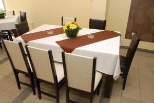 einen Tisch mit einem weißen Tischtuch und einer Blumenvase in der Unterkunft Linda Bed and Breakfast in Niš