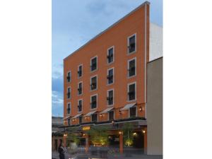 Un edificio di mattoni rossi con un uomo davanti di HOTEL LAGOS INN a Lagos de Moreno
