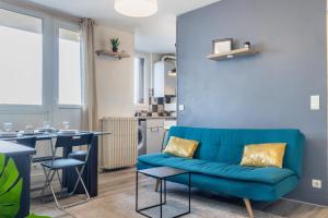 a living room with a blue couch and a kitchen at Le Cristol - joli T3 proche du Parc Dupeyroux in Créteil