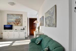 - un salon avec un canapé vert et une télévision dans l'établissement SOL LEONE, à Porto Torres