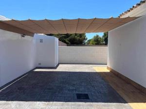 un patio con tenda da sole su un edificio con pavimento in mattoni di Villa Zen, La Barrosa a Cadice