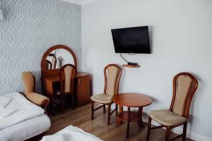 a living room with a table and chairs and a tv at Pokoje gościnne Biała Dama in Mławka