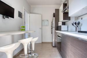 a kitchen with white counters and white stools at JOIVY Delightful flat with balcony in Milan