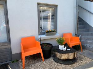 dwa pomarańczowe krzesła siedzące na boku domu w obiekcie Appartement 't Souterrain w Zandvoort