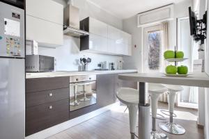 a kitchen with white cabinets and a table with green apples on it at ALTIDO Delightful flat with balcony in Milan