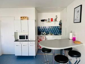 eine Küche mit einem weißen Tisch und schwarzen Stühlen in der Unterkunft Appartement 4 pers max à Seignosse le Penon in Seignosse