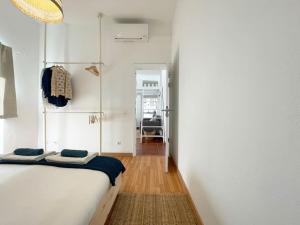 カスカイスにあるVillas Pedroso - Villa Palmiraのベッドルーム1室(白いベッド1台付)、廊下が備わります。
