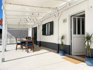 Dieses weiße Haus verfügt über eine Terrasse mit einem Tisch und Stühlen. in der Unterkunft Villas Pedroso - Villa Palmira in Cascais