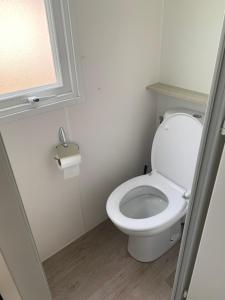 a white toilet in a bathroom with a window at Location Mobilhome in Narbonne-Plage