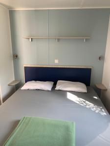 Un dormitorio con una cama con una manta verde. en Location Mobilhome en Narbonne-Plage