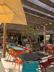 d'une terrasse avec des tables, des chaises et un parasol. dans l'établissement Location Mobilhome, à Narbonne-Plage
