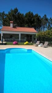 una gran piscina azul frente a una casa en Casa da Samouqueira, en Rogil