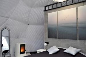 una camera da letto con un letto e una TV a parete di Glempings Anemones a Plieņciems