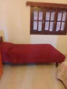 ein rotes Bett in einem Zimmer mit Fenster in der Unterkunft Rada in Embalse