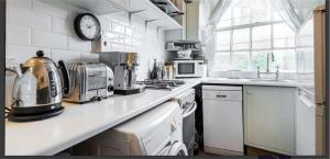 une cuisine avec des appareils blancs et une horloge murale dans l'établissement Charming 1-Wall Bed Comfortable Studio in NWLondon, à Londres