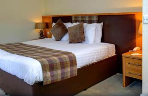 a hotel room with a large bed and a night stand at Buchanan Arms Hotel & Leisure Club in Drymen