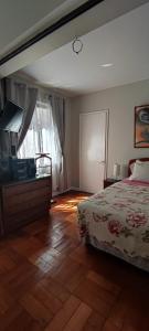 een slaapkamer met een bed en een dressoir met een televisie bij Departamento Pablo Neruda in Santiago
