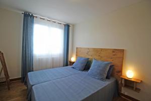 sypialnia z łóżkiem z niebieską pościelą i oknem w obiekcie Le magnolia w mieście Couzeix