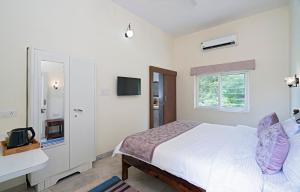 a white bedroom with a bed and a window at Madhav's Mallet - A Boutique Homestay in Jaipur