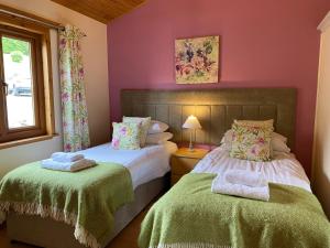 two beds in a room with pink walls at Copper Beech Lodge with Hot Tub in Cupar