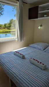 uma cama com duas almofadas com uma janela em Cottage flottant jacuzzi privé en option gamme supérieure em Saint-Jean-de-Losne