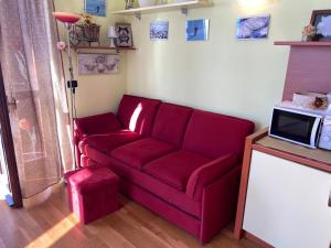 a living room with a red couch and a tv at Hotel Sole in Prato Nevoso