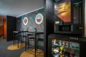 a bar with two stools and a refrigerator at Quick Palace Pau Zénith in Pau