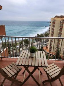 una mesa de madera y sillas en un balcón con vistas a la playa en Las Góndolas y el mar, en Almuñécar