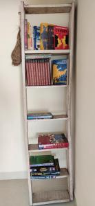 una mensola piena di libri accanto a un muro di Love & Peace Apartment a Jabalpur