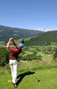 een man zwaaiend met een golfclub op een golfbaan bij Haus Krismer in Radstadt