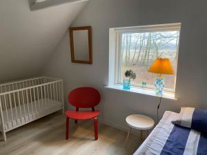 1 dormitorio con cama, silla roja y ventana en Skønt hus på landet tæt på Billund, en Give